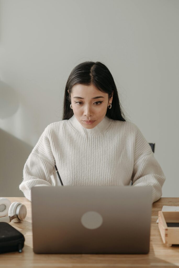 Asian woman in a cozy workspace focused on computer work, showcasing productivity in a modern setting.